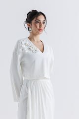 توب قصير بياقة V وتفاصيل وردية بارزة